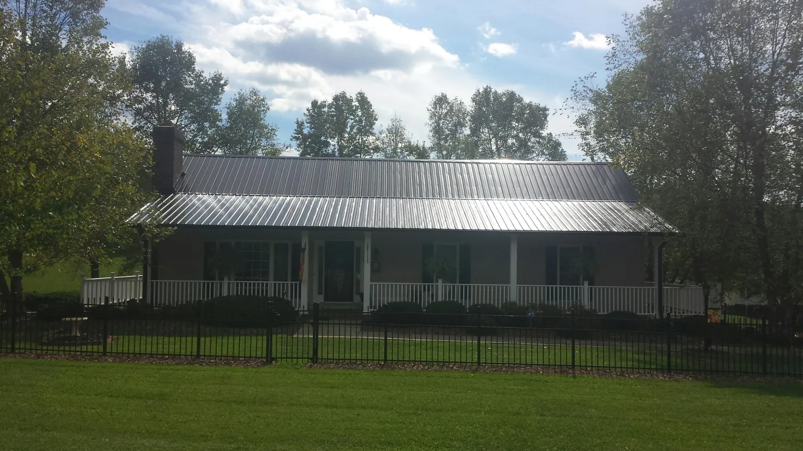 Gray metal roof on a brick ranch with a full width front porch — Gutter Guard Installation work by our crew in Colora