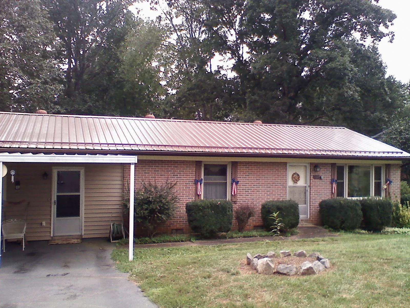 Bronze metal roof and carport on a brick ranch home — Roof Repair work by our crew in Colora
