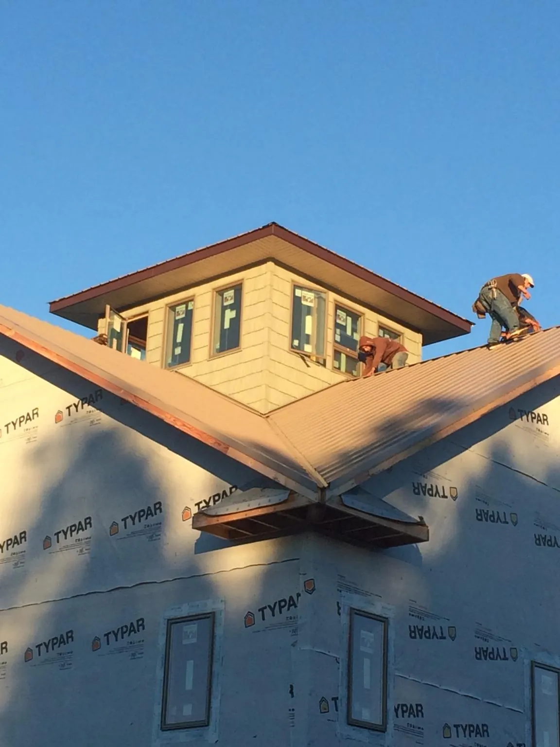 Roofers working around a rooftop cupola on a new metal roof at sunset — Roof Waterproofing in Colora by Roofing Brothers